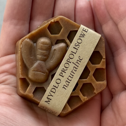 Mydło propolisowe naturalne z woskiem pszczelim w kształcie plastra miodu trzymane w dłoni ręcznie robione mydło do skóry problematycznej